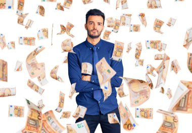 İş kıyafetleri giyen genç, yakışıklı, şüpheci ve gergin bir adam. Yüzünde çapraz kollarla onaylanmayan bir ifade var. negatif kişi.