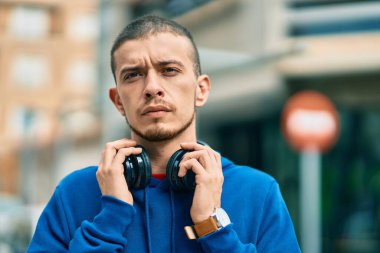 Şehirde kulaklık takan ciddi bir suratı olan genç bir İspanyol.