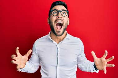 Genç İspanyol işadamı gömlek ve gözlük takıyor. Deli gibi bağırıyor ve agresif bir ifade ve kollarla bağırıyor. hüsran kavramı. 