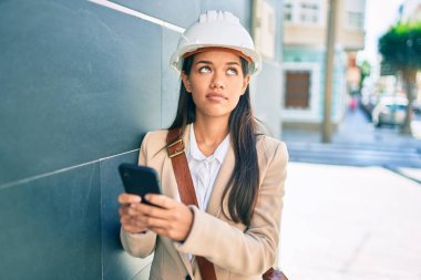Şehirde akıllı telefon kullanan, ciddi bir suratı olan genç Latin mimar kız..