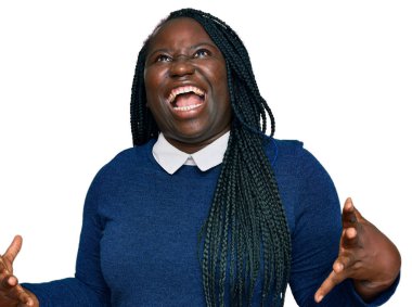 Saçları örgülü genç siyahi bir kadın çılgın ve kızgın bir şekilde bağırıyor ve agresif bir ifade ve kolla bağırıyor. hüsran kavramı. 