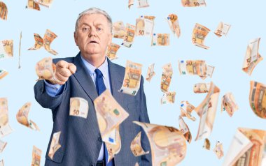 İş ceketi giyen yaşlı, gri saçlı adam kameraya kızgın ve sinirli olduğunu gösteriyor.