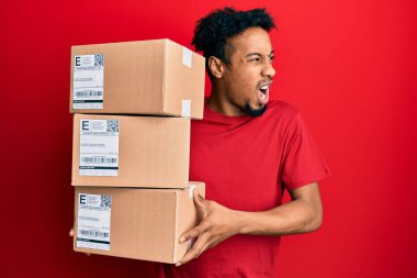 Sakallı, elinde teslimat paketleri olan genç Afro-Amerikan bir adam öfkeli ve öfkeli çığlıklar atıyor. Öfkeyle bağırıyor. öfke ve agresif konsept. 