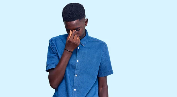 身穿休闲服的年轻的非洲裔美国人疲倦地揉揉鼻子和眼睛 感到疲劳和头痛 压力和挫败感概念 — 图库照片