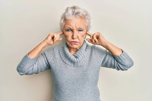 Senior grey-haired woman covering ears with finger depressed and worry for distress, crying angry and afraid. sad expression.