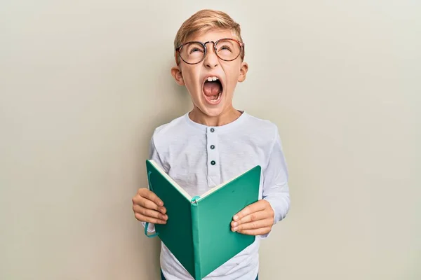 Pequeno Garoto Caucasiano Lendo Livro Usando Óculos Irritado Louco Gritando — Fotografia de Stock