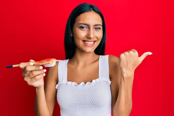 Jovem Morena Comendo Sushi Camarão Usando Pauzinhos Apontando Polegar Para — Fotografia de Stock