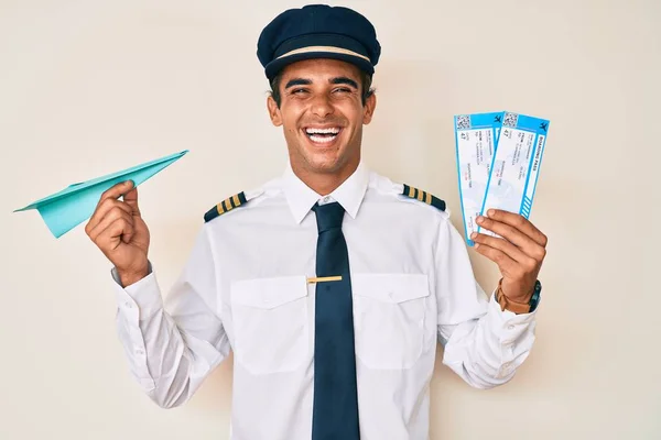 Junger Hispanischer Mann Flugzeugpilotenuniform Mit Papierflugzeug Und Bordkarte Lächelt Und — Stockfoto