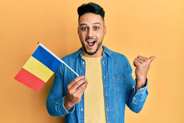 Joven Árabe Sosteniendo Bandera Romania Apuntando Con Pulgar Hacia Lado —  Fotos de Stock