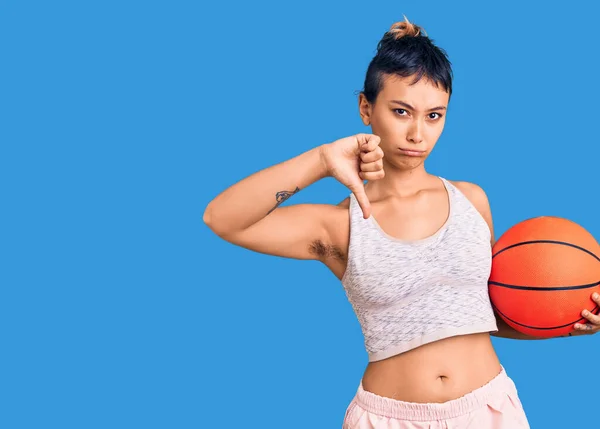 怒っている顔でバスケットボールボールを保持若い女性 親指ダウンで嫌いを示す負の記号 拒絶概念 — ストック写真