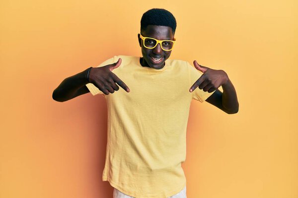 Young african american man wearing casual clothes and glasses looking confident with smile on face, pointing oneself with fingers proud and happy.