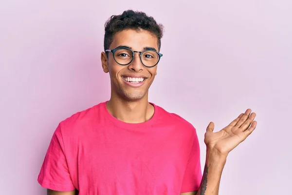 Молодий Афроамериканець Одягнений Окуляри Над Рожевим Фоном Усміхається Радісно Презентує — стокове фото
