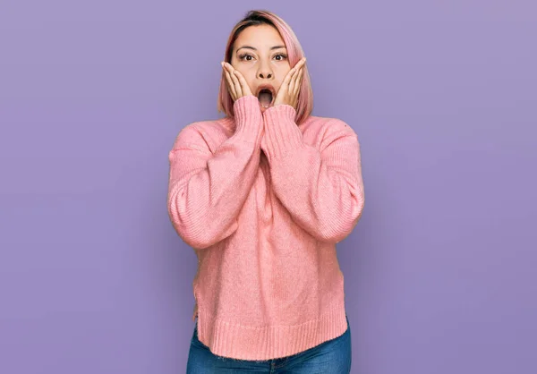 ピンクの髪を持つヒスパニック系の女性は カジュアルな冬のセーターを着て恐れてショックを受け 驚きと驚きの表情で手で顔 — ストック写真