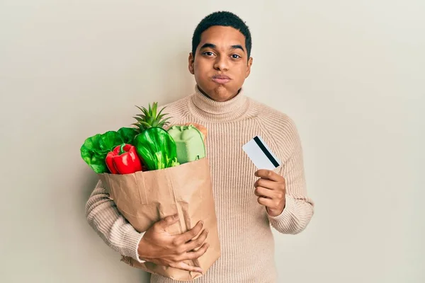 Joven Hombre Hispano Guapo Sosteniendo Comestibles Tarjetas Crédito Inflando Mejillas —  Fotos de Stock