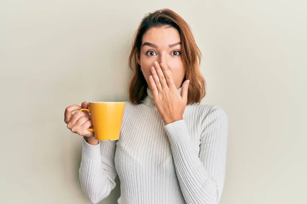 Jovem Caucasiana Segurando Café Cobrindo Boca Com Mão Chocado Com — Fotografia de Stock