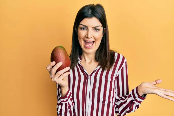 Young Hispanic Woman Holding Mango Celebrating Achievement Happy Smile Winner — Stock Photo, Image