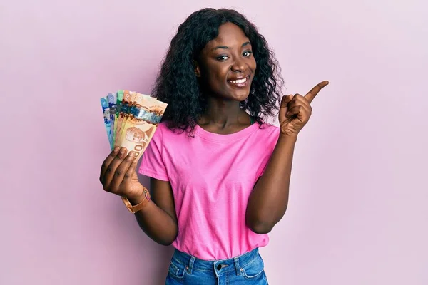 Krásná Africká Mladá Žena Drží Kanadské Dolary Úsměvem Šťastný Ukazující — Stock fotografie