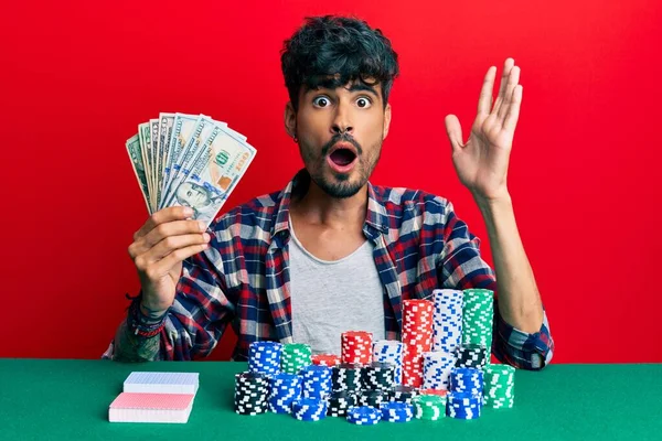 Jovem Hispânico Sentado Mesa Com Fichas Poker Cartas Segurando Dólares — Fotografia de Stock