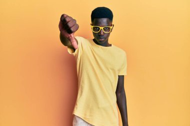 Genç, Afro-Amerikan bir adam günlük kıyafetler ve gözlük takıyor mutsuz ve kızgın görünüyor reddediliyor ve olumsuz jestler yapıyor. kötü ifade. 