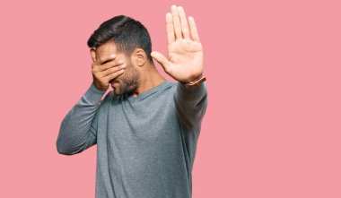 Yakışıklı, günlük kıyafetler giyen, elleriyle gözlerini kapatan, üzgün ve korku ifadeli hareketler yapan İspanyol. utangaç ve olumsuz kavram. 