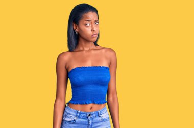 Genç Afro-Amerikan kadın günlük yazlık kıyafetler giyiyor şüpheci ve gergin, sorun yüzünden surat asıyor. negatif kişi. 