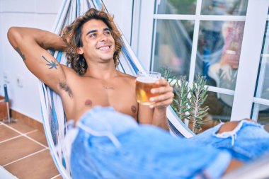 Genç İspanyol adam terasta hamakta uzanmış bira içerek rahatladı..