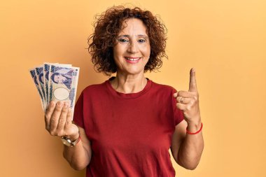 Güzel, orta yaşlı olgun bir kadın elinde 5000 Japon doları ile bir fikir veya soru işareti ile gülümsüyor. 