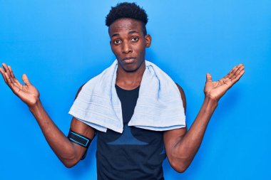 Genç Afro-Amerikan erkek spor giysisi ve havlu giyiyor. Kolları açık ve kafası karışık. Hiç bir fikrim yok.. 