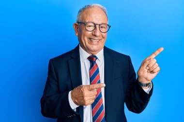 İş elbisesi giymiş, kravat takmış, gülümseyen ve kameraya bakan beyaz bir adam.. 