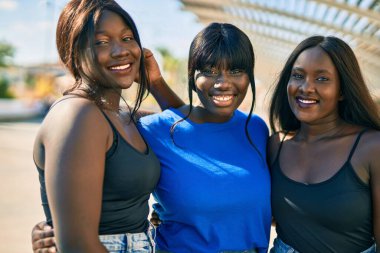 Üç Afrikalı Amerikalı arkadaş gülümsüyor. Mutlu bir şekilde kucaklaşıyorlar..