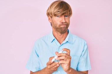 Genç sarışın adam glikoz ölçer kullanıyor şüpheci ve gergin, sorun yüzünden surat asıyor. negatif kişi. 