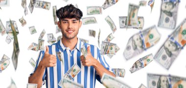 Gündelik kıyafetler giyen genç İspanyol adam. Başarı işareti yapıyor. Elleriyle olumlu jest yapıyor. Neşeli ifade ve kazanan jest.