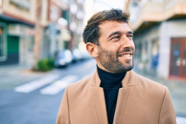 Zarif ceket giyen yakışıklı iş adamı dışarıda mutlu bir şekilde gülümsüyor.