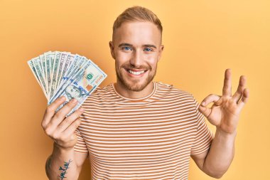 Elinde dolar tutan beyaz bir adam parmaklarıyla imza atıyor, gülümsüyor ve mükemmel bir sembol. 