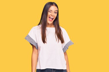 Gündelik kıyafetler giyen genç İspanyol kadın kameraya seksi bir ifadeyle bakıyor, neşeli ve mutlu bir yüzle.. 