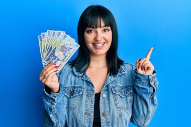 Genç İspanyol kadın elinde 100 Romen Ley banknotuyla mutlu bir şekilde gülümsüyor. 