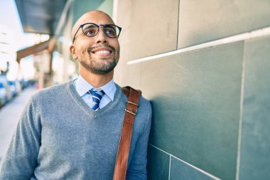Genç Afrikalı Amerikalı iş adamı gülümsüyor. Şehrin duvarına yaslanmaktan mutlu..