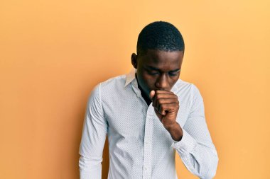 Genç Afro-Amerikalı bir adam günlük giysiler giyiyor kendini iyi hissetmiyor ve soğuk algınlığı veya bronşitin belirtisi olarak öksürüyor. sağlık hizmeti kavramı. 