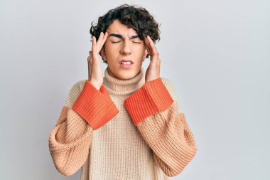 İspanyol genç adam, stresten dolayı elleri başının üstünde, sıradan bir kazak giyiyor. migren ağrısı. 