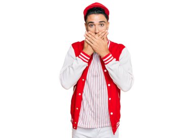 Beyzbol üniforması giyen sakallı genç adam yanlışlıkla ağzı ellerle kapatırken şok oldu. gizli kavram. 