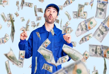 İspanyol ressam üniforması giyen genç adam şaşırmış ve şaşırmış bir şekilde yukarı bakıyor ve parmaklarıyla işaret ediyor ve kollarını kaldırıyor..