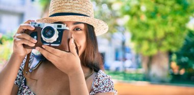 Şehrin caddesinde gezen eski model kamera kullanan genç Latin kadın..