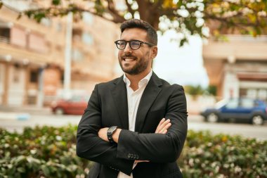 Kollarını kavuşturmuş genç İspanyol işadamı şehirde mutlu bir şekilde gülümsüyor..