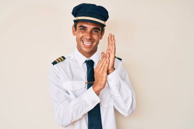 İspanyol asıllı genç adam, uçak pilotu üniforması giyiyor, alkışlıyor, alkışlıyor, mutlu ve neşeli, gururlu elleri bir arada. 