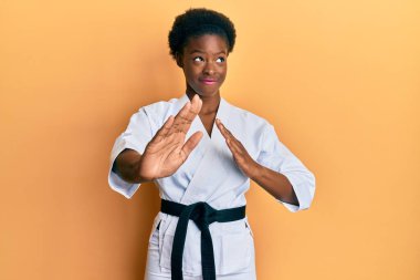 Genç Afrikalı Amerikalı kız karate kimonosu ve siyah kuşak takmış gülümseyip yan tarafa bakıyor ve şöyle düşünüyor:. 