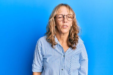 Orta yaşlı, sıradan kıyafetler giyen ve gözlüklü bir kadın. Kameraya bakıp havada öpücük yolluyor. Güzel ve seksi. aşk ifadesi. 