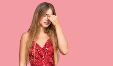 Yazlık elbise giyen güzel sarışın kadın yorgun burnu ve gözleri ovuşturup yorgun ve baş ağrısı çekiyor. Stres ve hüsran kavramı. 