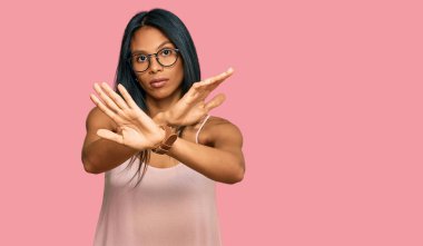 Genç Afrikalı Amerikalı kadın, günlük kıyafetler ve gözlük takıyor. Reddedilme ifadesi, kollar ve avuç içleri kesişiyor. Negatif işaret veriyor, kızgın surat. 