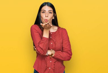 Gündelik giysiler giymiş genç İspanyol bir kadın kameraya bakıp havada bir öpücük savuruyor ve sevimli ve seksi oluyor. aşk ifadesi. 