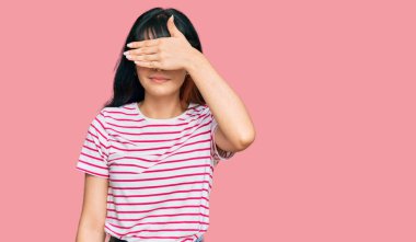 Latin asıllı genç bir kız. Günlük kıyafetler giyip, gözlerini eliyle kapatıyor. Ciddi ve üzgün görünüyor. Görme, saklama ve reddetme konsepti 